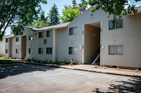 A row of beige apartment buildings with trees in the background.