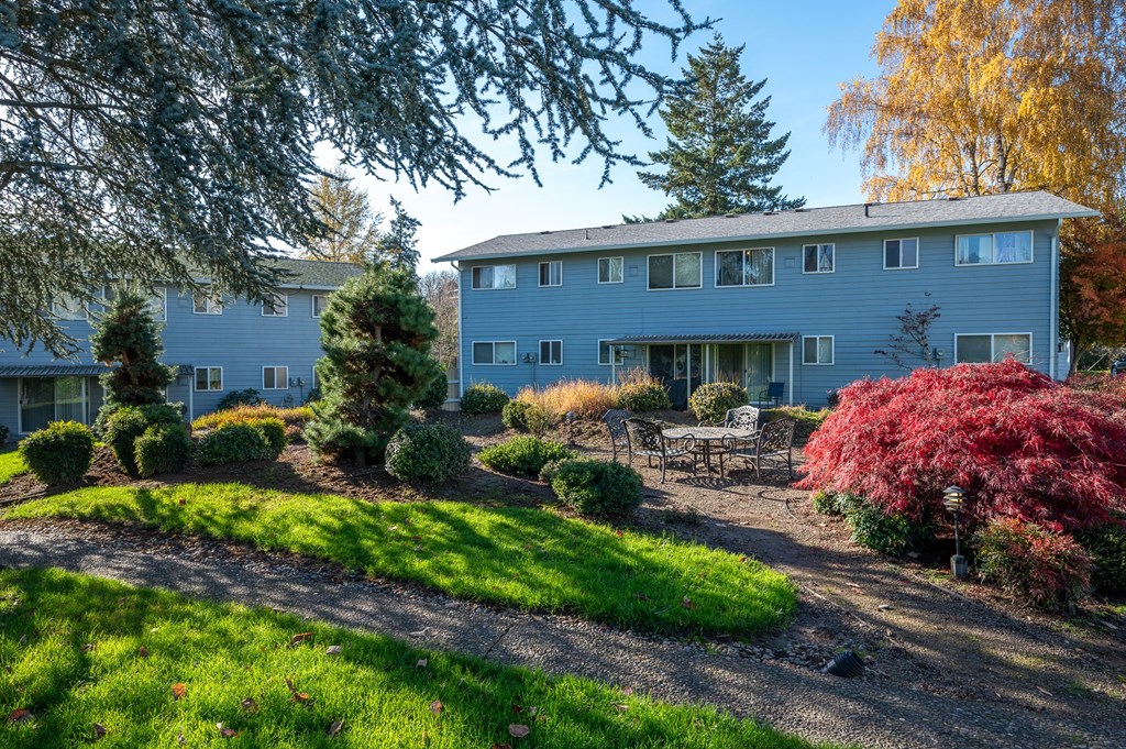 a view of a blue house with a garden and a patio