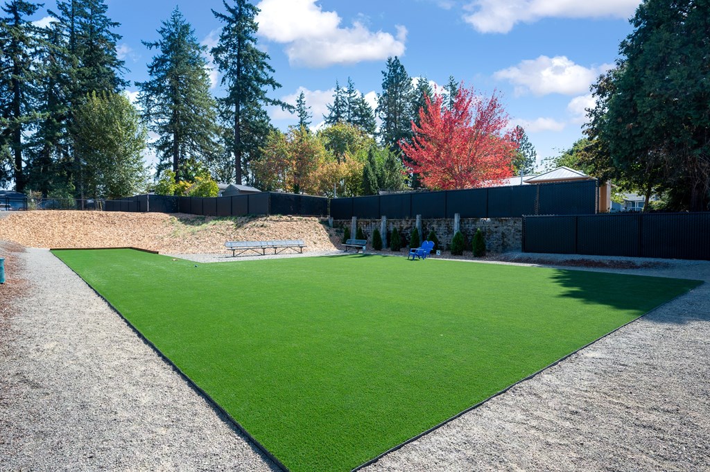 A park with a green lawn and a black fence.