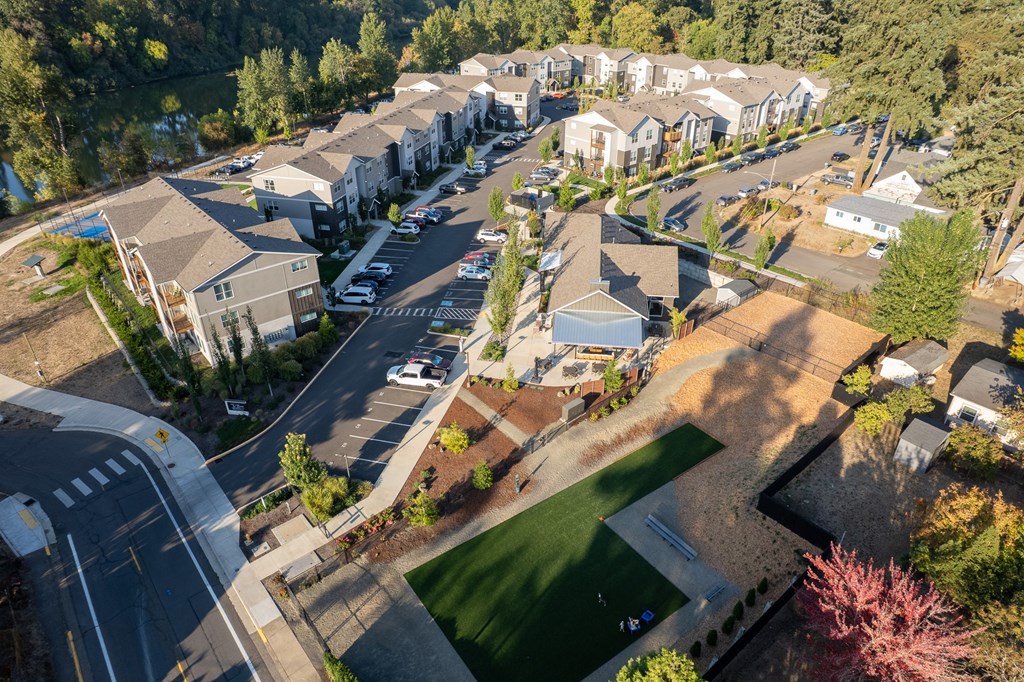 A bird's eye view of a residential area with houses, cars, and a green lawn.