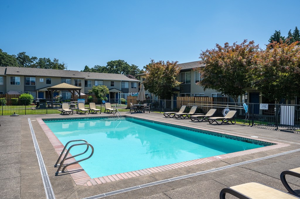 A swimming pool surrounded by lounge chairs and trees.