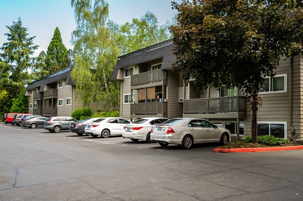 A parking lot with cars and apartment buildings in the background.