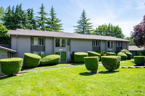 a gray house with rounded hedges in front of it