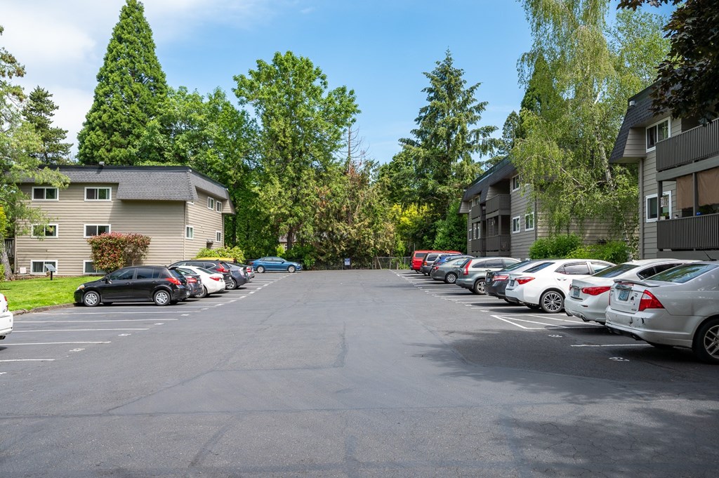 A parking lot with cars and apartment buildings in the background.