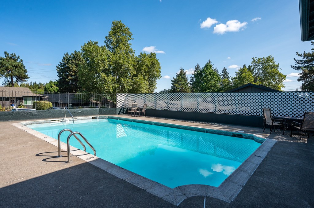 a swimming pool with chairs and a fence around it