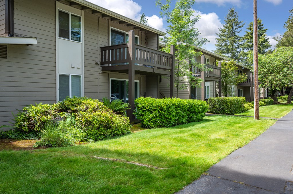 an exterior view of an apartment building with green grass and bushes