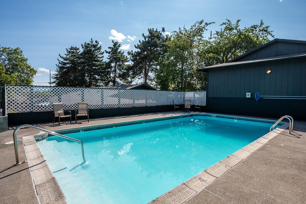 a swimming pool with a fence and chairs around it