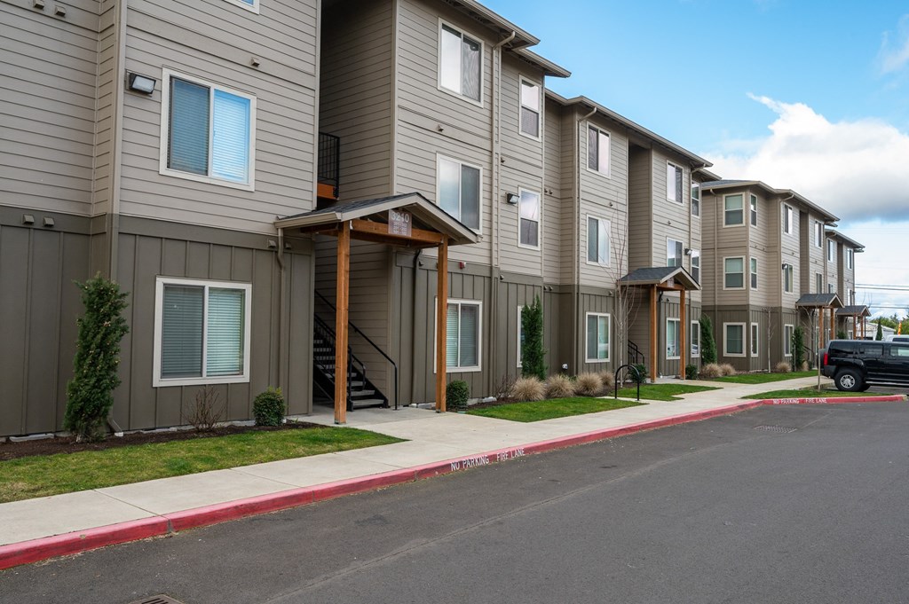 A row of modern apartment buildings with a black car parked in front.
