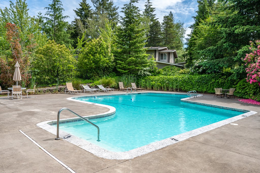 a swimming pool with chairs around it and a house in the background