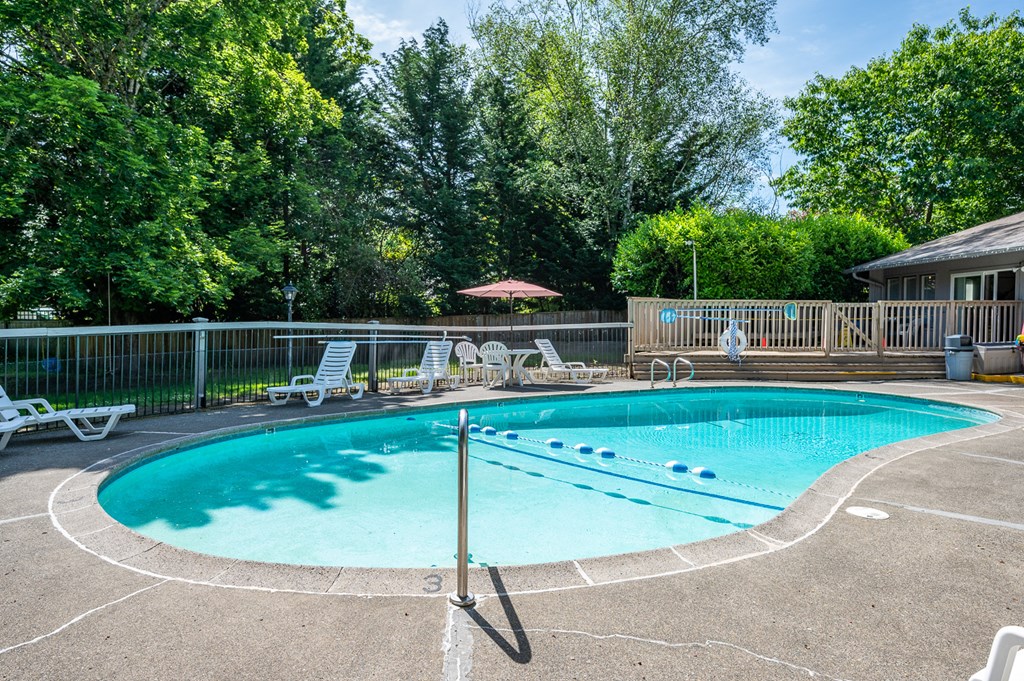 a resort style pool with chairs and a fence around it