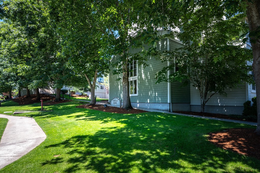 a house with a green lawn and trees in front of it