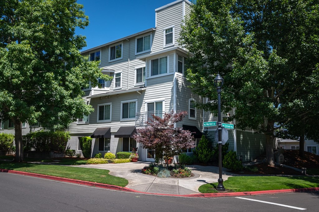 an apartment building with grey siding and a street sign in front of it