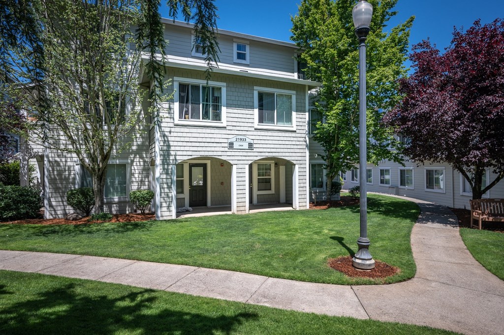 an apartment building with a lawn and trees in front of it
