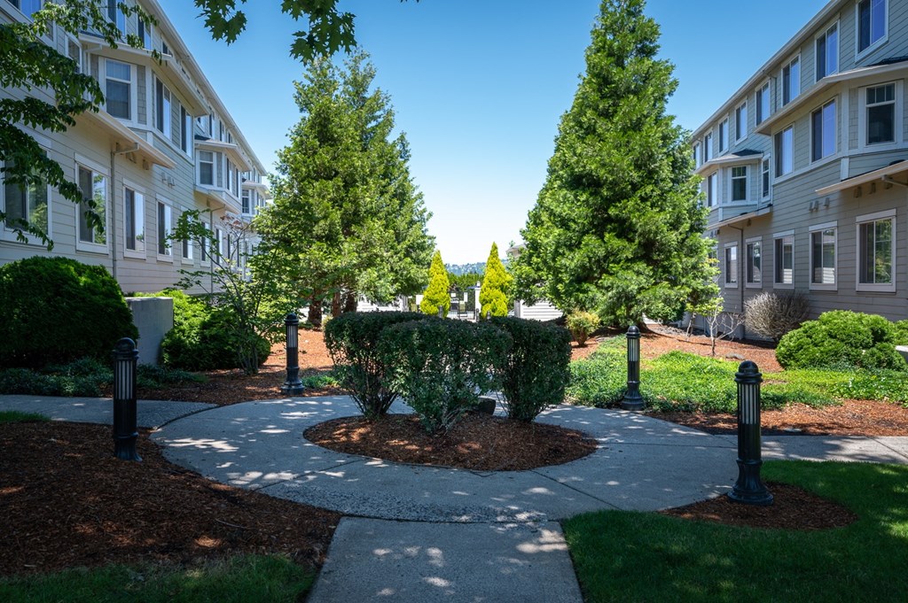 a circular walkway with trees and bushes in front of an apartment building