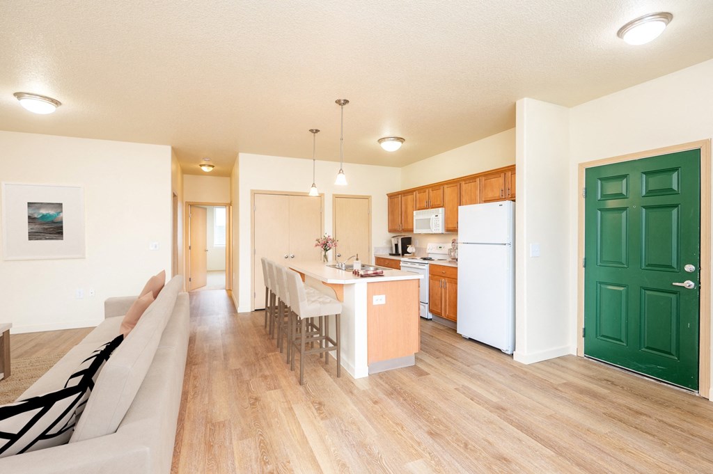 an open kitchen and living room with a dining table and a refrigerator