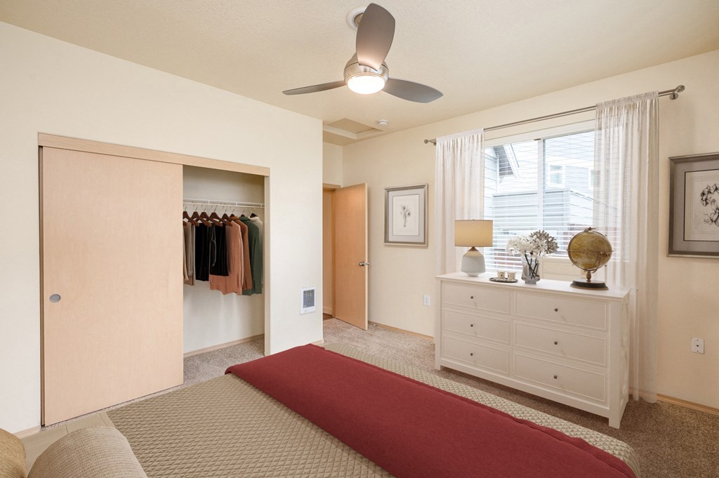 a bedroom with a bed and closet and a ceiling fan