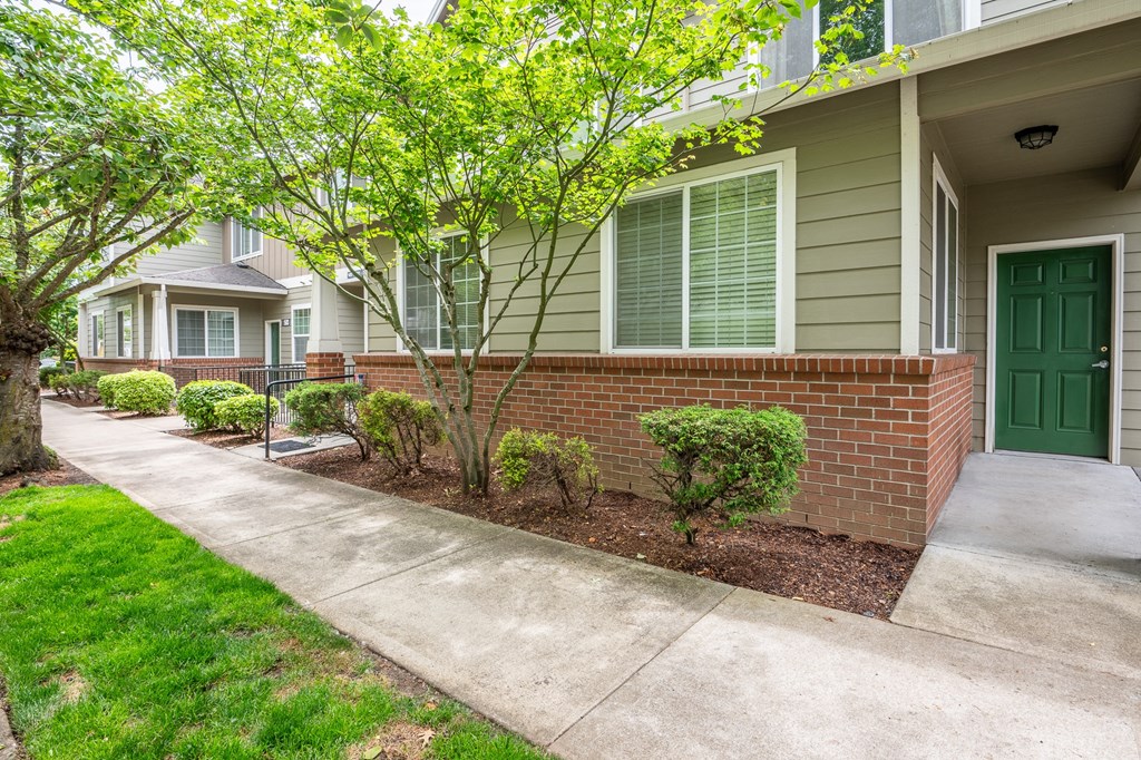 a sidewalk in front of a building with a green door