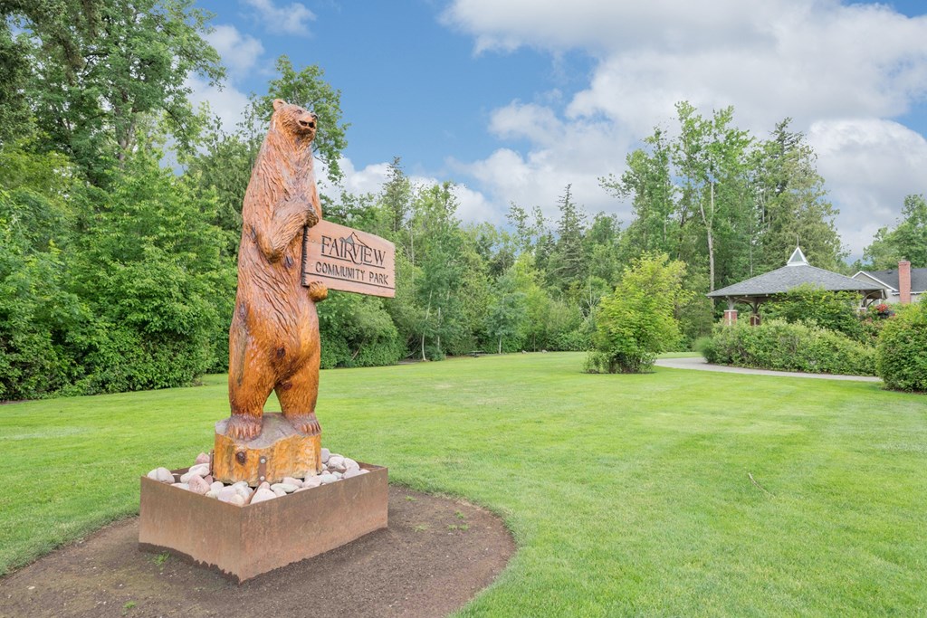 a statue of a bear holding a sign in a park