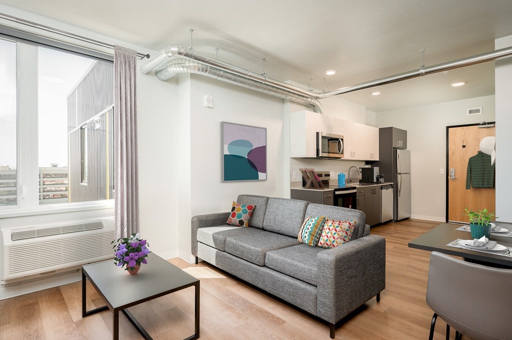 A living room with a grey couch, a coffee table, and a painting on the wall.