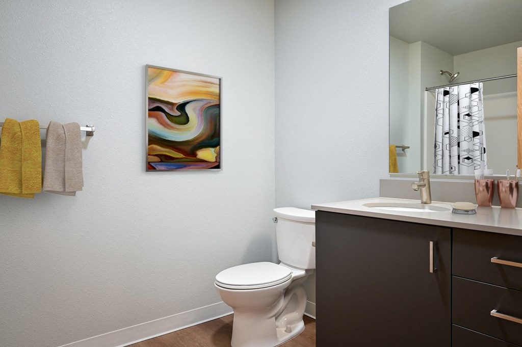A bathroom with a toilet, sink, and a painting on the wall.