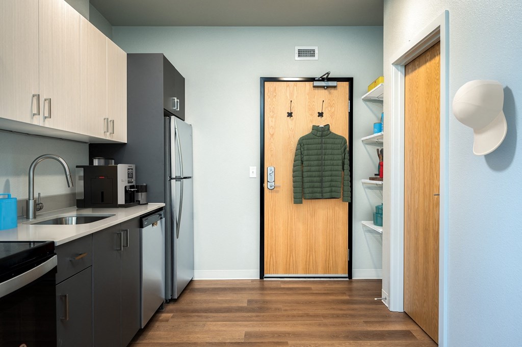 A kitchen with a wooden door and a green sweater hanging on it.