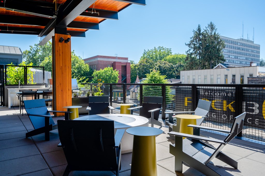 a rooftop patio with tables and chairs and a building in the background