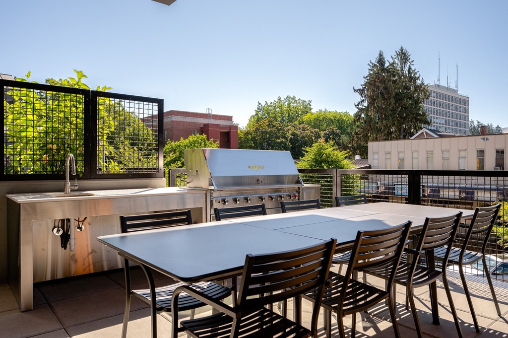 an outdoor patio with a table and chairs and a grill