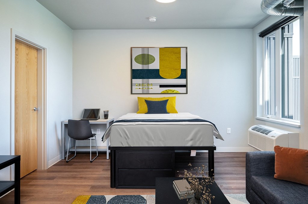 A bedroom with a bed, desk, and couch.