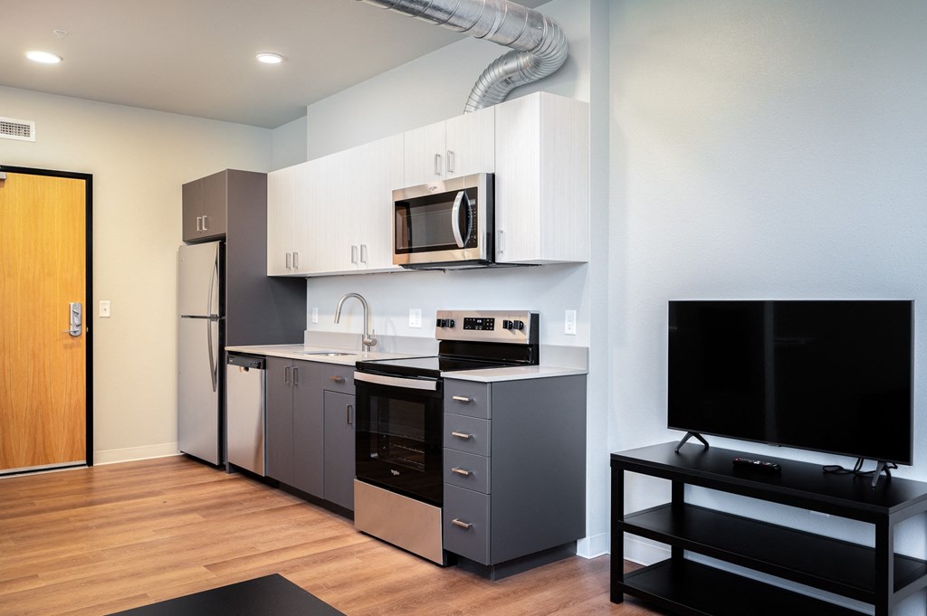 a kitchen with stainless steel appliances and a tv in a apartment