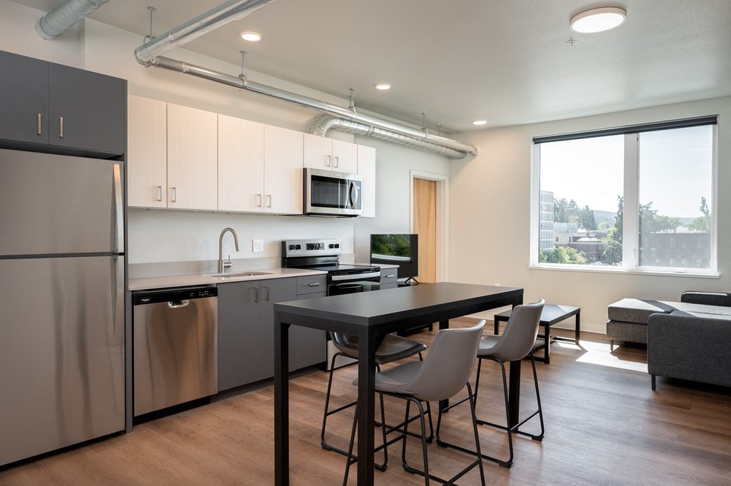 a kitchen and living room with a refrigerator and a table and chairs