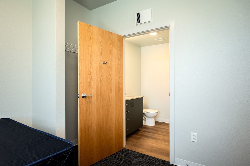 a bedroom with a door leading into a bathroom with a toilet