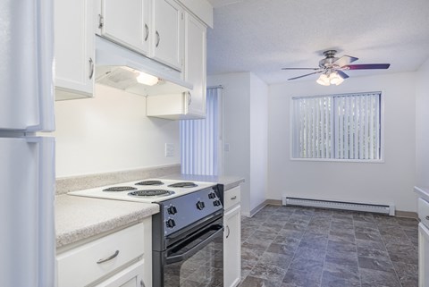 a kitchen with white cabinets and a stove and a ceiling fan