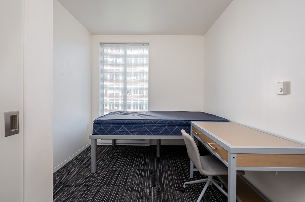 A bedroom with a bed, desk, and chair.