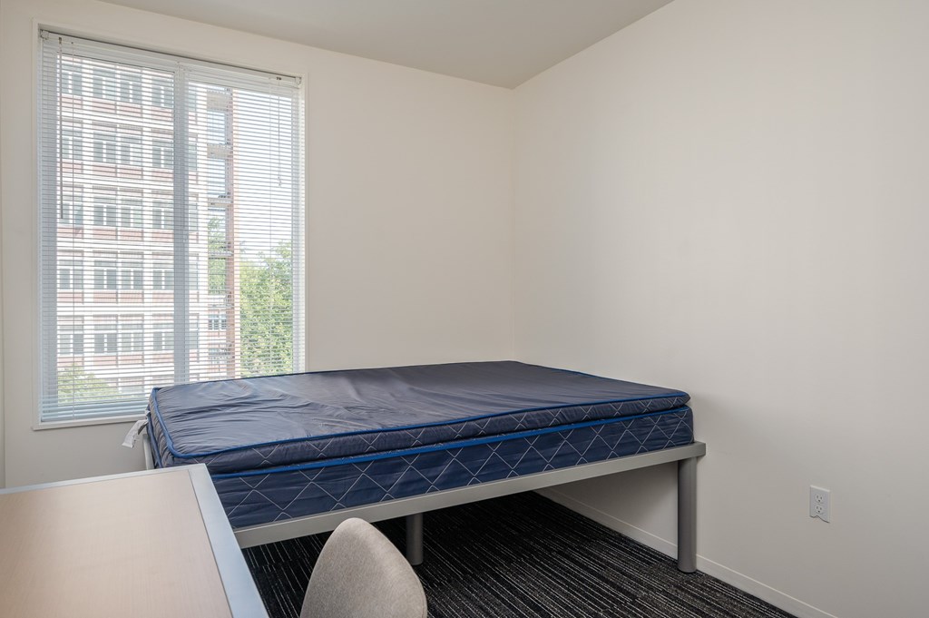 A bed with a blue mattress is in a room with a window.