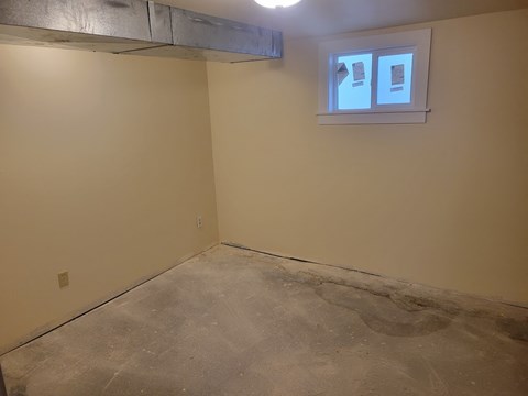 A room with a window and a concrete floor.