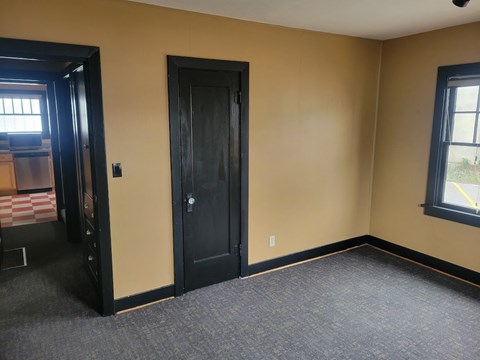 A room with a black door and a window with a yellow line on it.