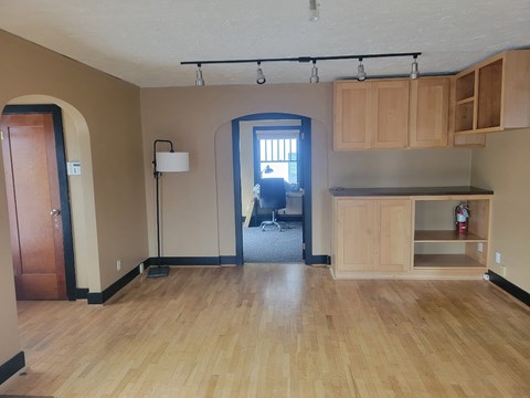A room with wooden floors and a kitchenette.