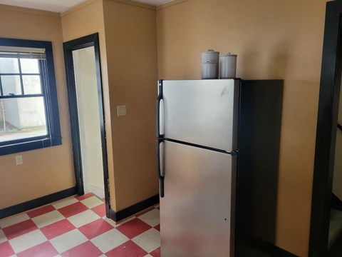 A black refrigerator with two cans on top of it in a room with a checkered floor.