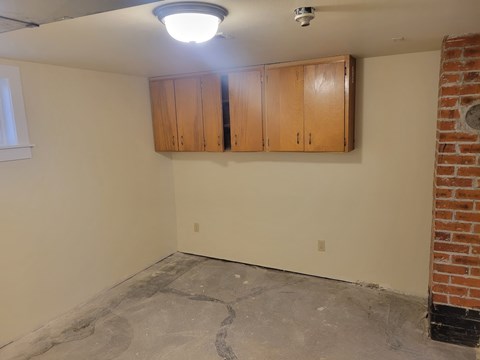 A room with a brick wall and a pair of wooden cabinets.