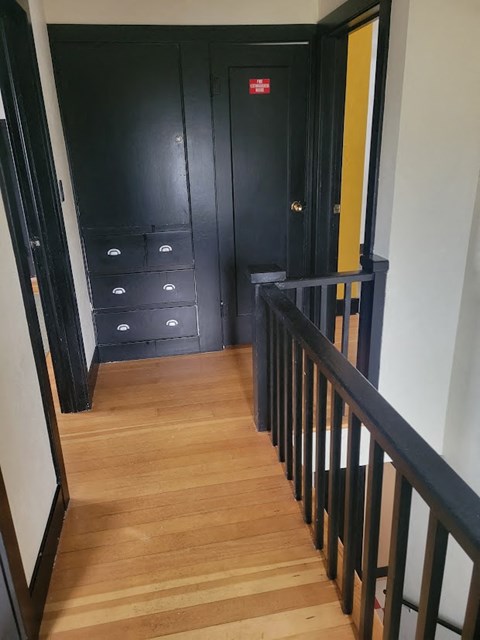 A hallway with a black door and drawers underneath it.