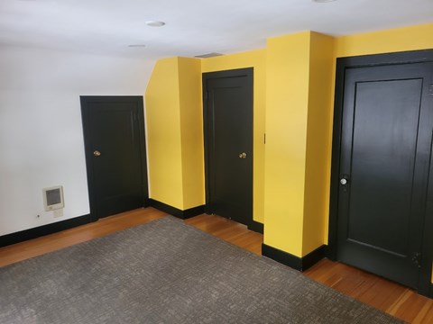 Three black doors are lined up against yellow walls.