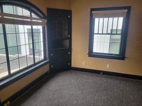 A room with a black door and a window with blinds.