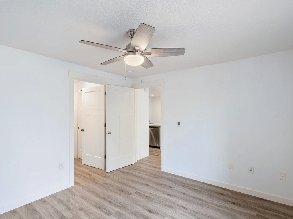 a bedroom with white walls and a ceiling fan