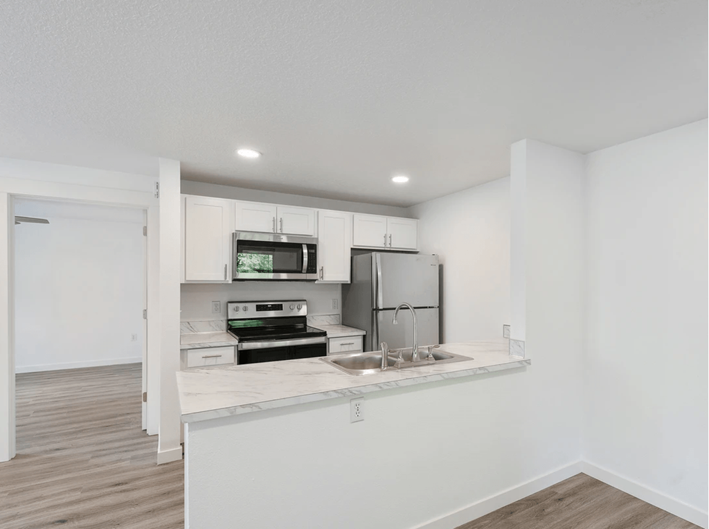 a kitchen with white walls and a wooden floor