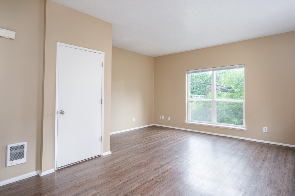 an empty living room with wood floors and a window