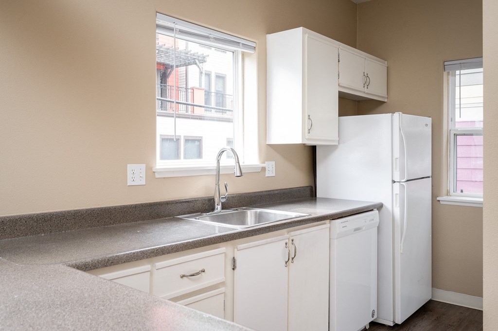 a kitchen with white cabinets and a sink and a refrigerator