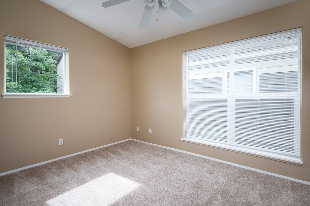 an empty bedroom with a large window and a ceiling fan