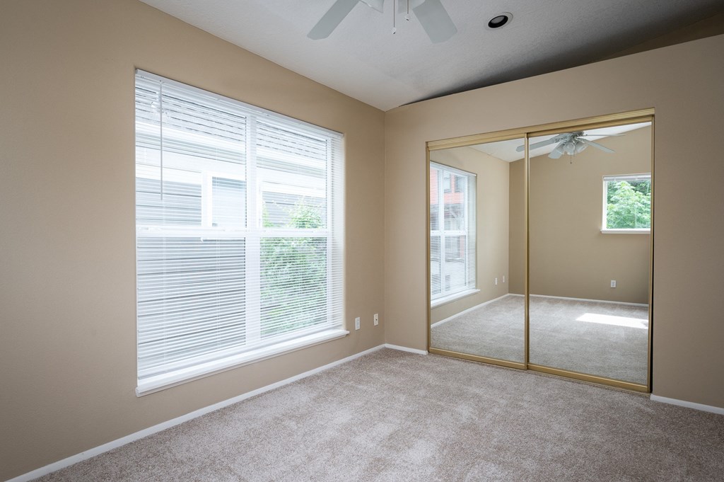 an empty bedroom with a large window and a mirror