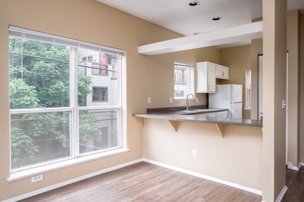 an empty living room with a large window and a kitchen