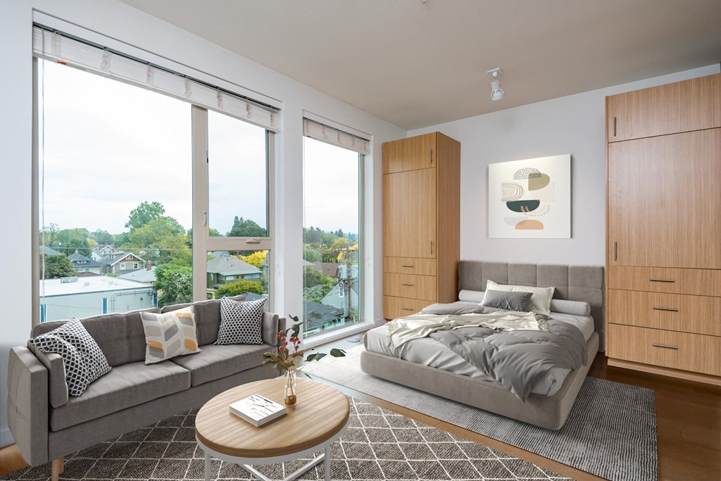 a bedroom with a bed and a couch and large windows